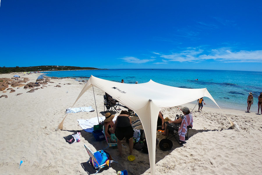 Lightweight beach shelter setup on the beach with people sitting underneath