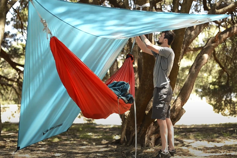 Man setting up Hammock Tarp over his hammock