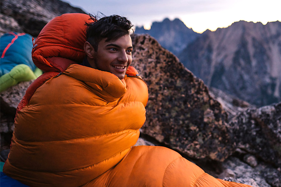 Man sitting in Marmot sleeping bag in alpine conditions