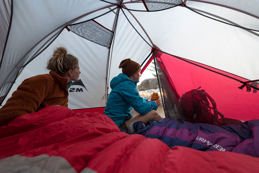 Two people liying in MSR sleeping bags in a tent