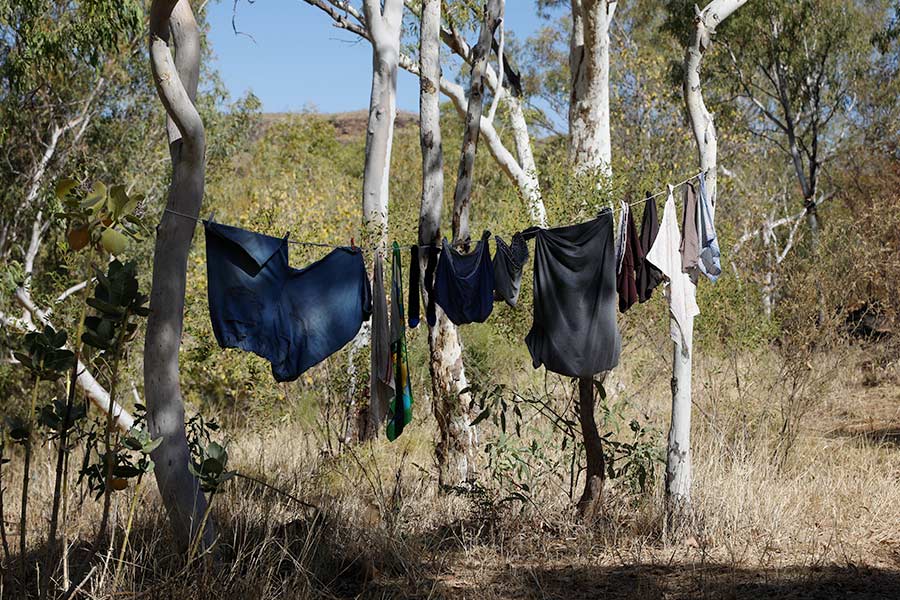 Clothes hung on a pegless clothesline between trees in the bush