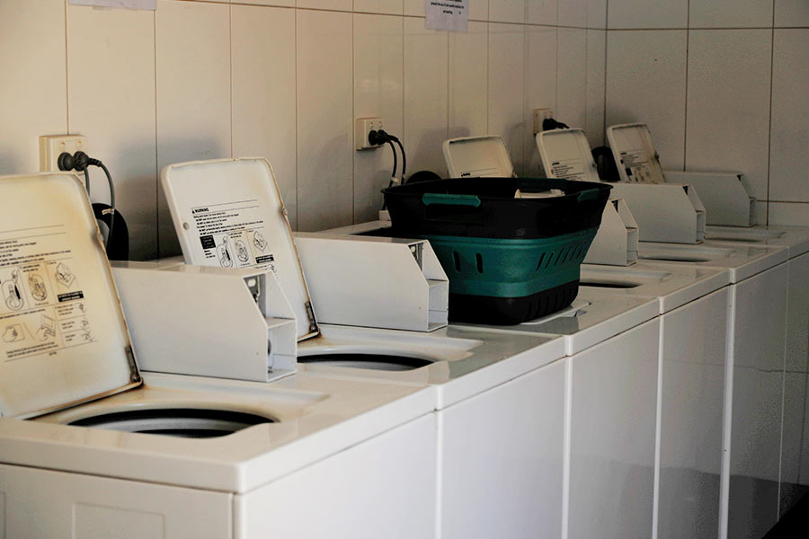 A line of coin operated washing machines in a laundry room