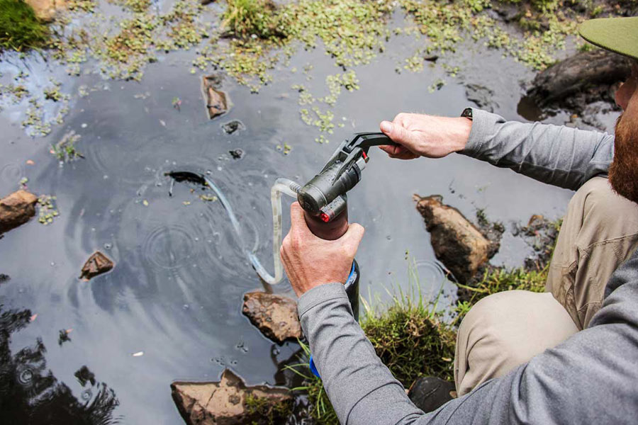 A man using a water purifier to clean water from a river