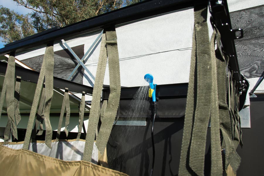 A portable shower set up alongside a camper trailer