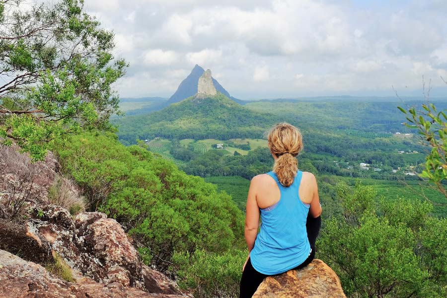 A woman sits at the top of a mountain taking in the view