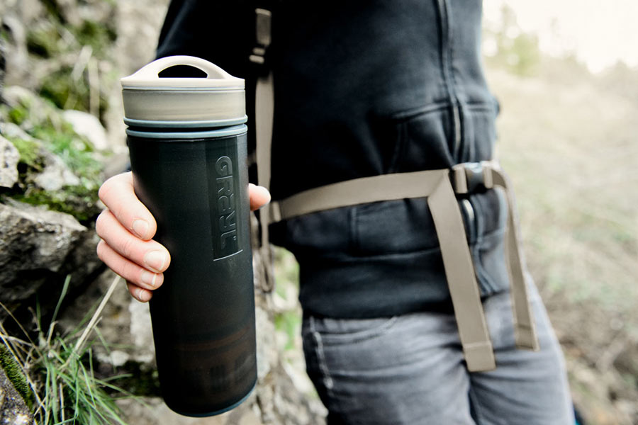 A hiker holds a Grayl filter water bottle
