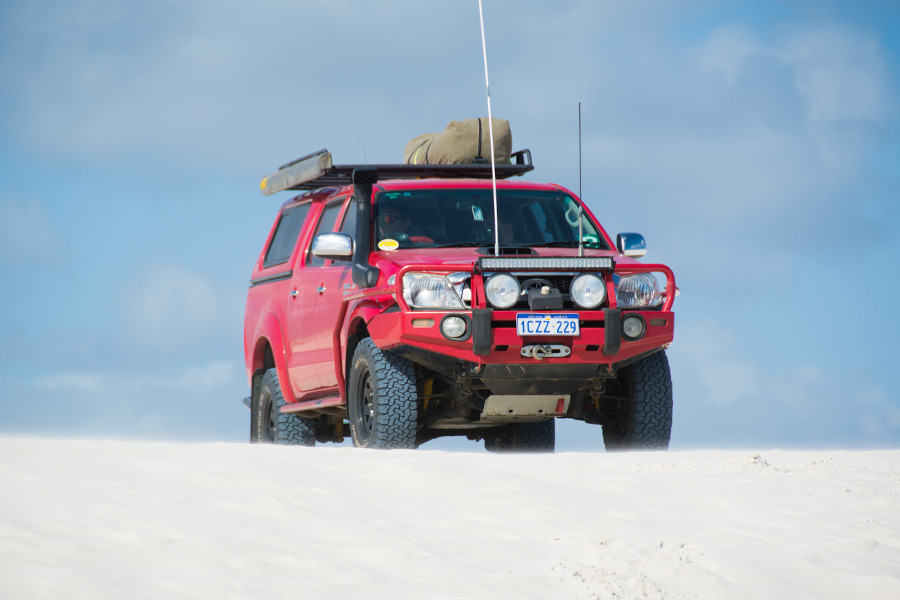 A red 4WD at the top of a sand dune