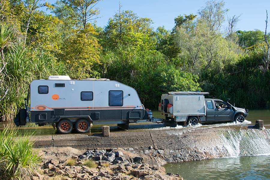A 4WD towing a caravan at a water crossing.