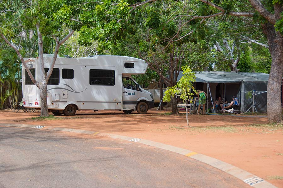 A motorhome parked near a tent at a campsite.