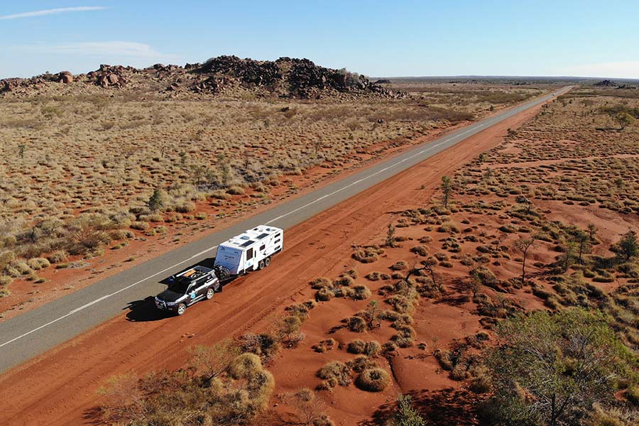 A vast stretch of open road, with a vehicle and caravan parked alongside it.