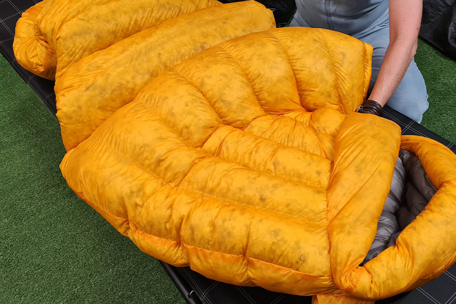 A down sleeping bag inside out showing the bright yellow lining.