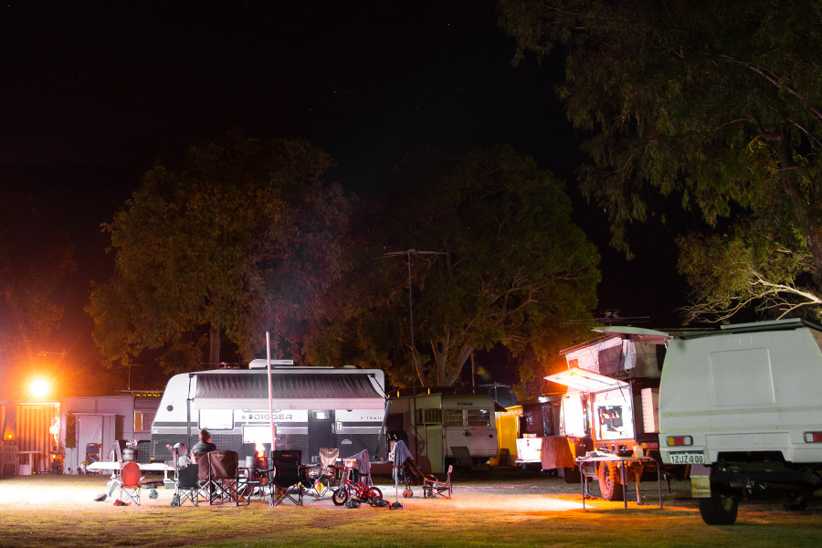 A night time scene at a campground with caravans and a communal area set up.