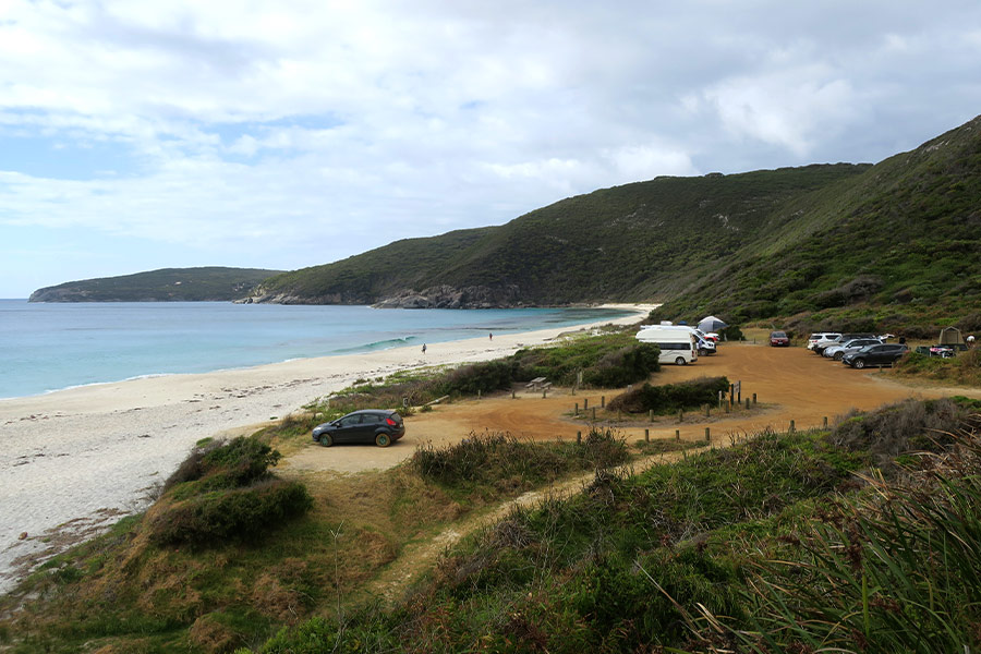Shelley Beach carpark and campground set back from the sand and surrounded by rolling green hills.
