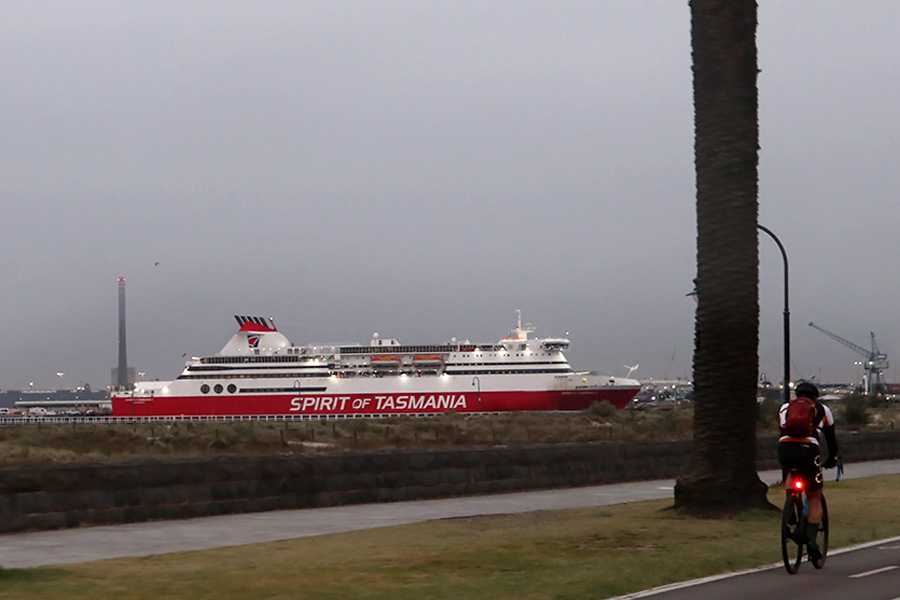Spirit of Tasmania ferry docked at the Victorian port. Image taken from the road approaching and includes the back of a cyclist with reflector light. 