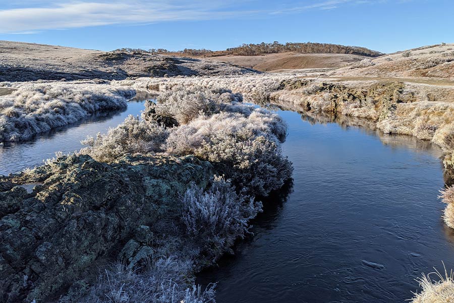 Image an icy stream and frost covered ground across Long Plain in Kosciuszko National Park.