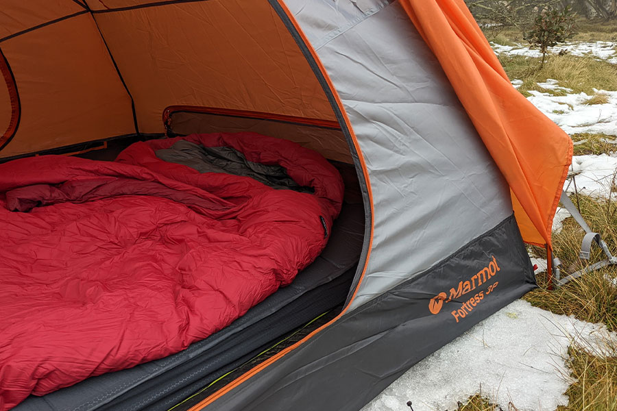 Image shows the interior of a Marmot Fortress 3P hiking tent pitched in the snow with an insulated Zempire Monstamat and down sleeping bag.