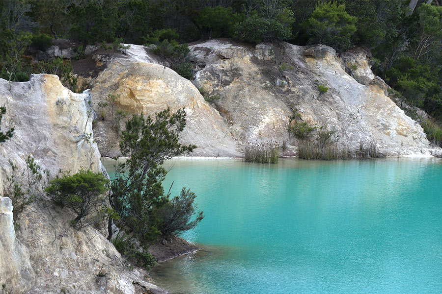 Stunning ice blue lake waters framed by rock walls and scattered vegetation.