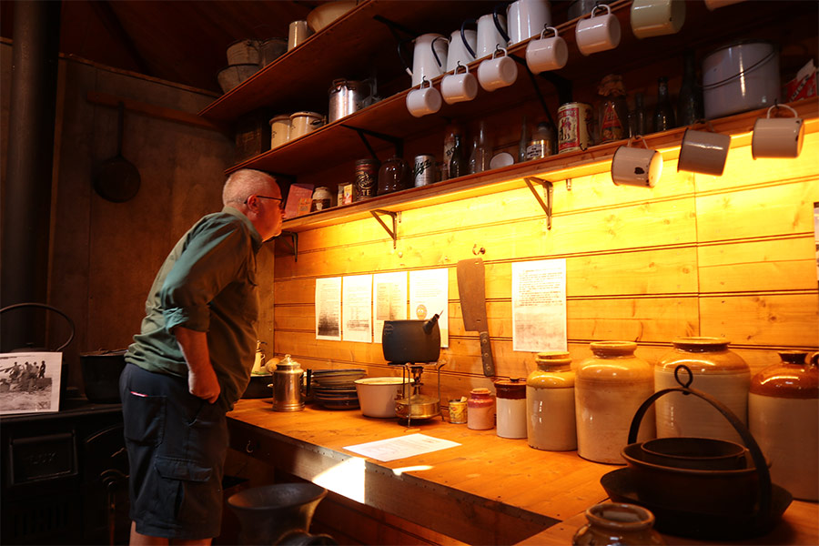 A man leans in close to read the historical information inside Mawson's Hut replica in Tasmania.