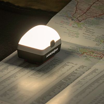Hard Korr's Dual Colour Uni Lantern is on and resting atop an open map, illuminating the page.