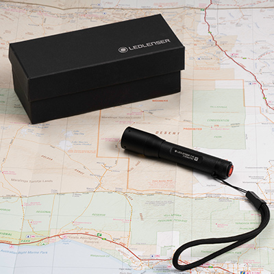 The tiny but mighty Lenlenser P3 Flashlight is sitting on top of an open map with the closed gift box nearby.