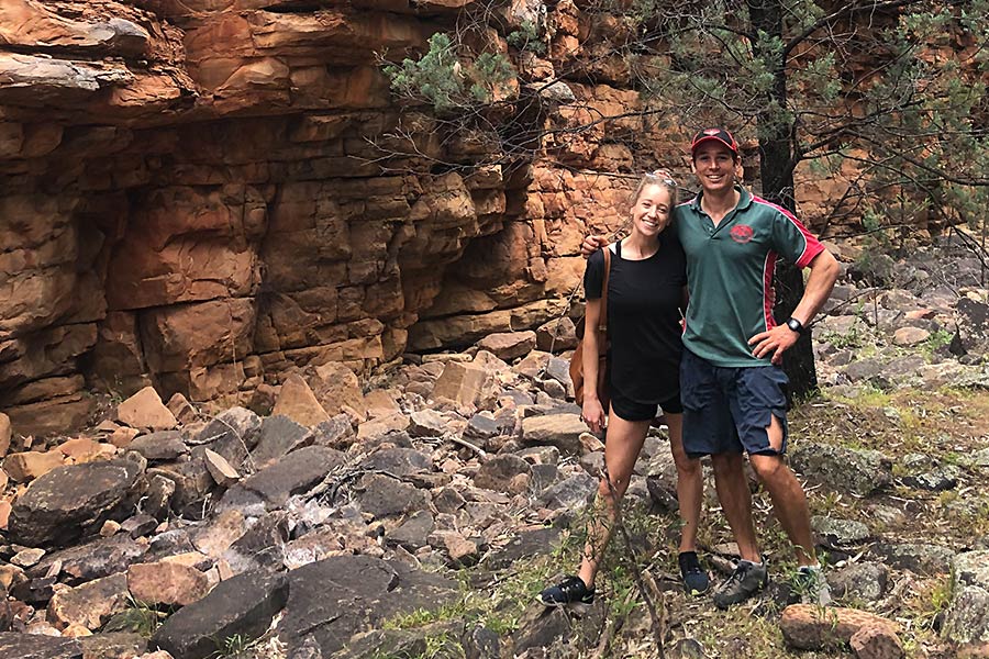Adult siblings stand and pose for the camera on a rocky gorge floor in the Australian Outback.