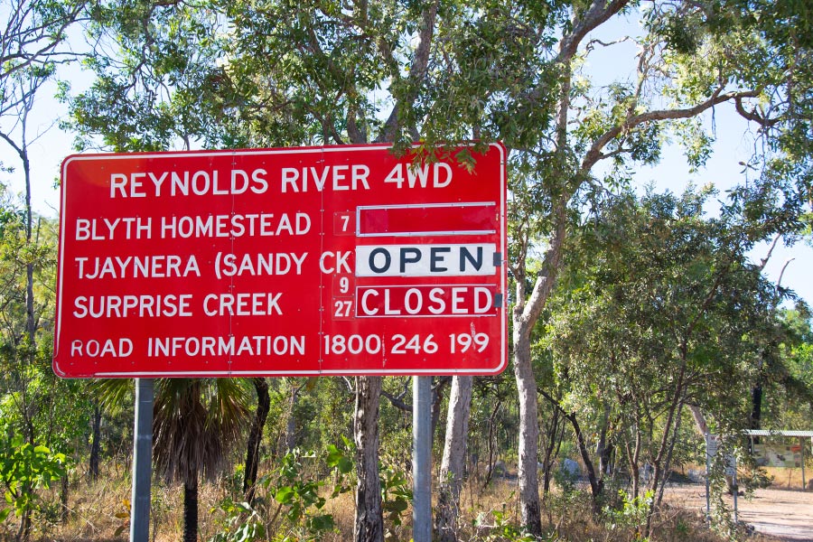 A bright red sign clearly stating open/close information on the Reynolds River 4WD track in Litchfield National Park. 