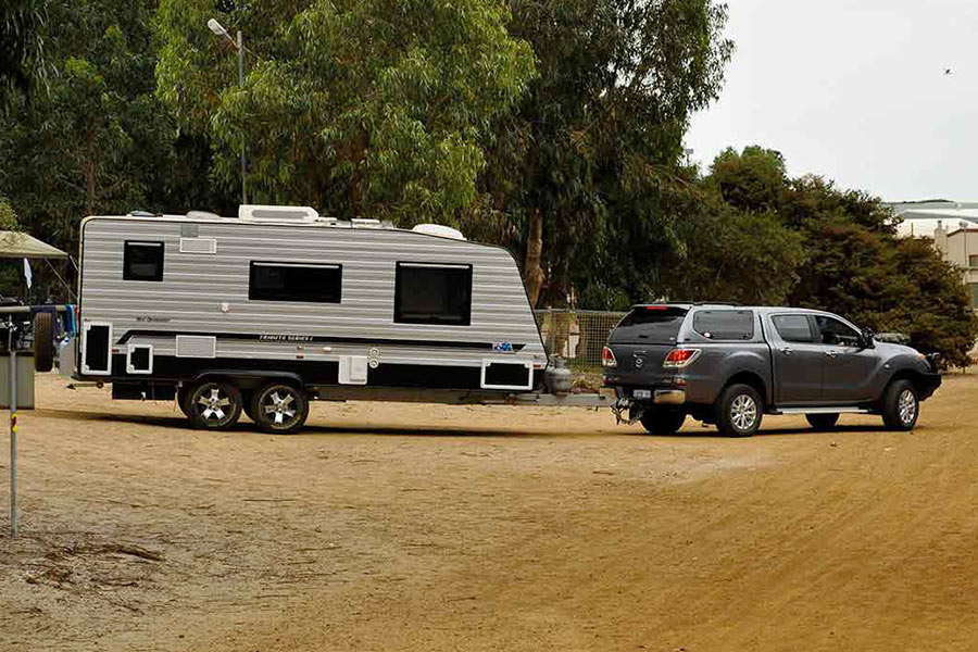 A black dual cab ute with hard canopy towing a large caravan.