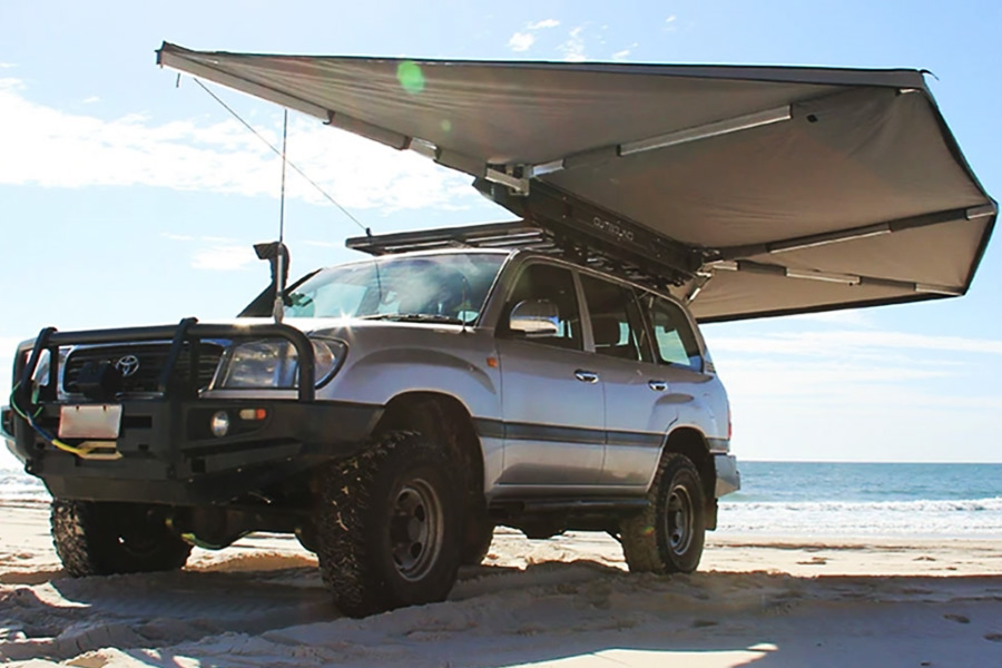 A 4WD is parked on the beach, hosting Supa Peg's Outbound Shield 6 Freestanding Awning. 