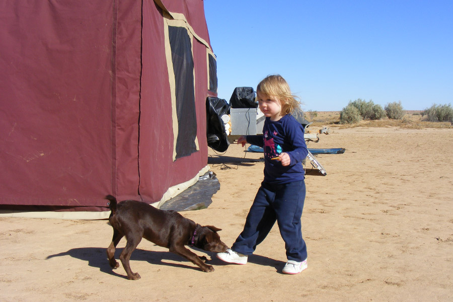 Girl with puppy playing outdoors, west of Birdsville.