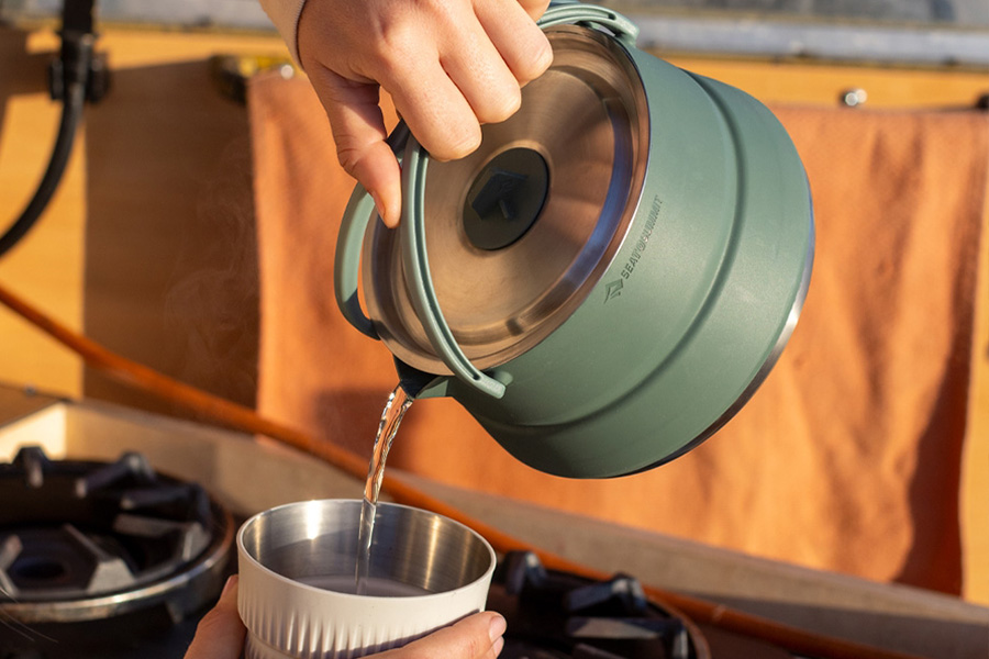 The Sea to Summit Detour kettle pouring hot water into a cup at sunrise. 