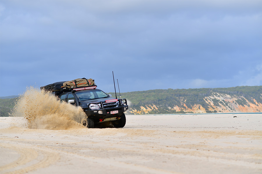 A 4WD skidding through the sand on a beach. 