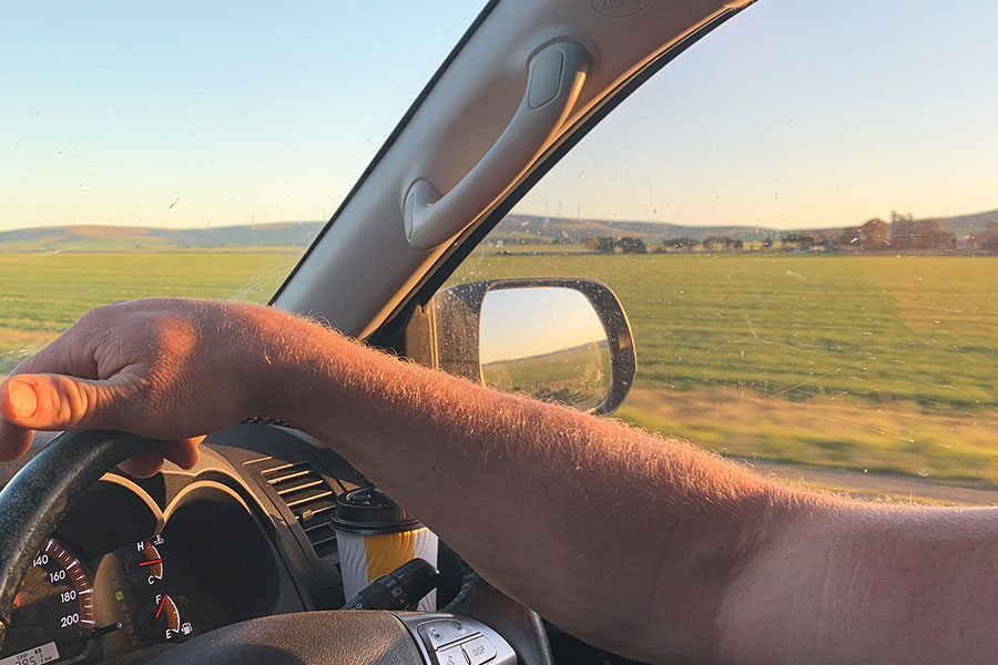 An arm on the steering wheel at sunset. 