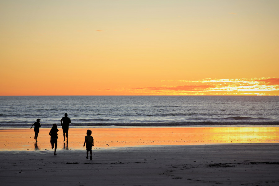 A silhouette of family running into the sunset on a beach.  