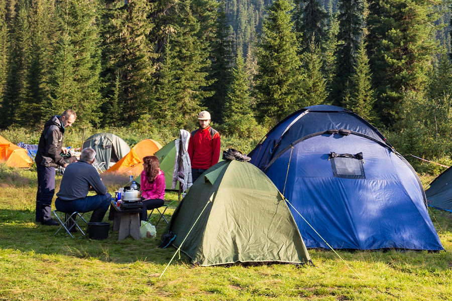 A group of campers surrounded by multiple colourful tents. 