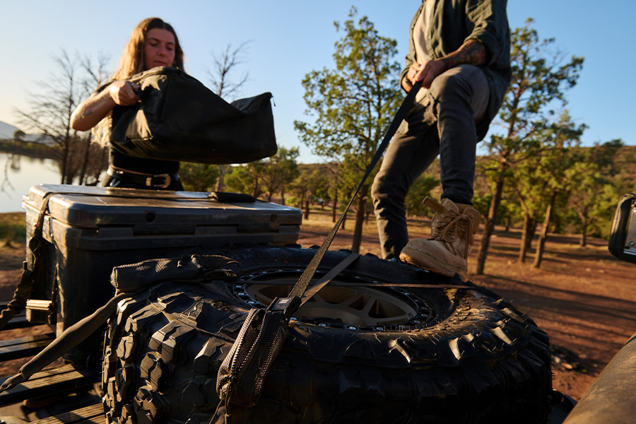 Two campers strapping their gear with tie-downs.