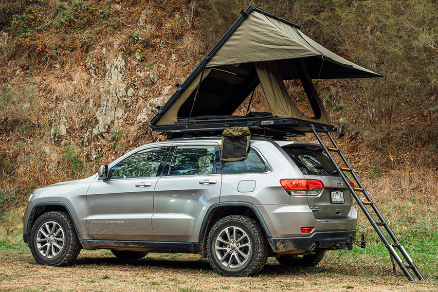 Ben and Lauren climb the ladder of the latest lightweight rooftop tent innovations! An SUV with a lightweight rooftop tent on top, and an extended ladder.