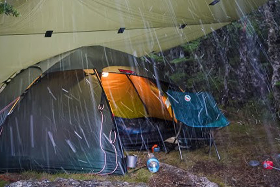 A tent and chair sitting out in storm.