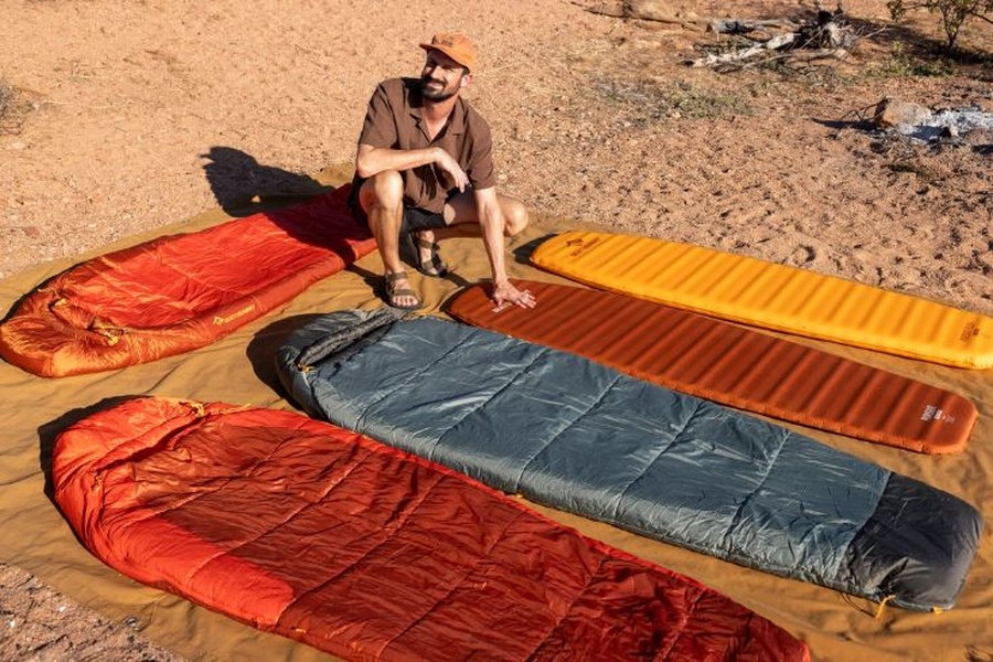Picture of Tim on a field test with sleeping bags and mats laid neatly out on a groundhseet