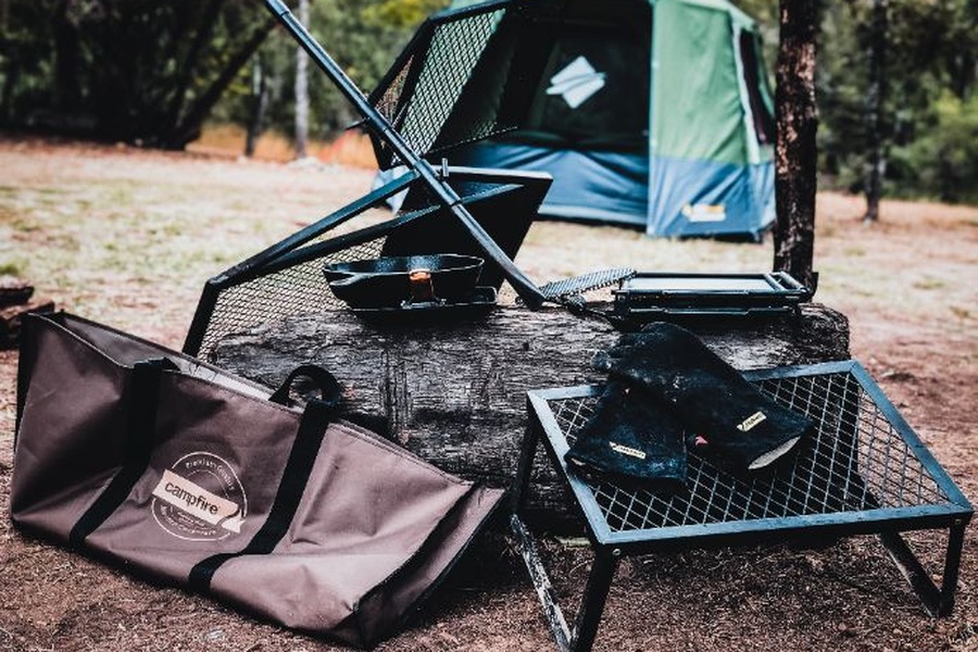 Image of campfire cooking equipment against a log with a campfire in the background